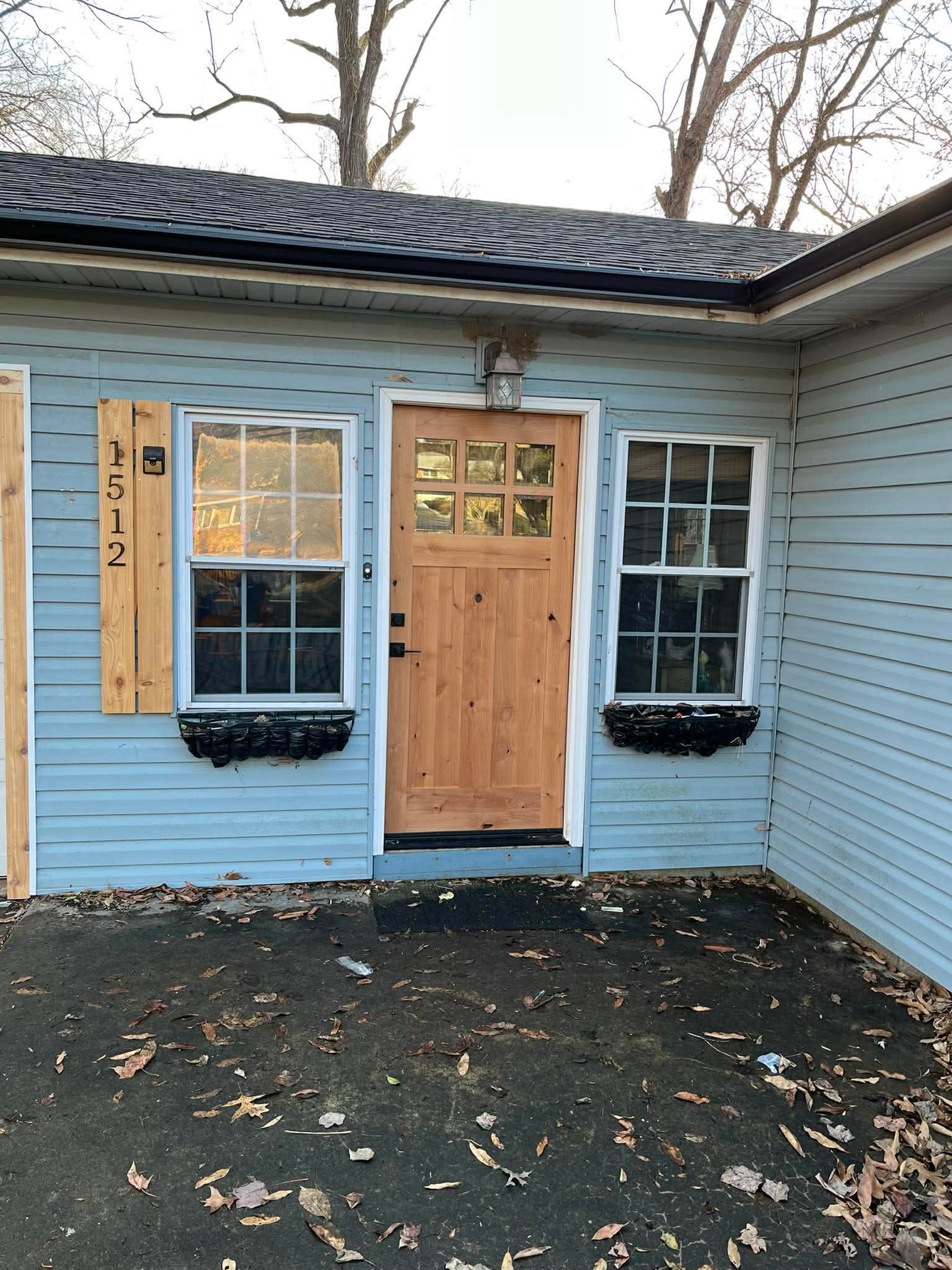 Craftsman-style front entry door with glass panels and new blue siding