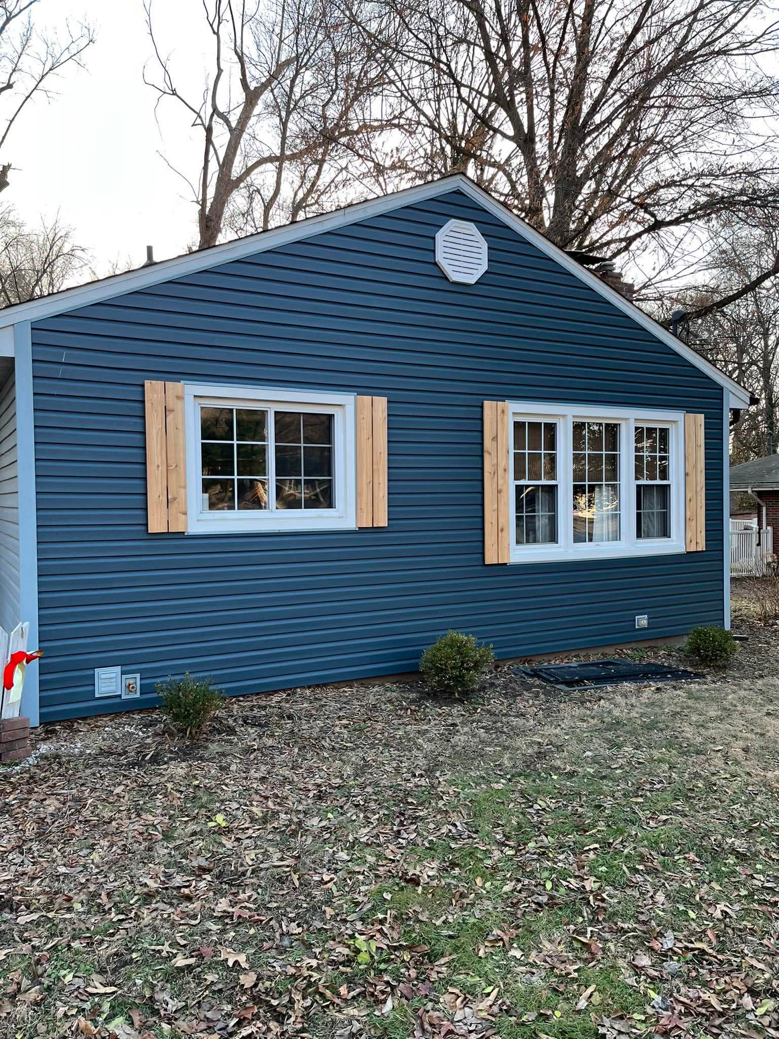 Home exterior with new blue siding and cedar board-and-batten shutters